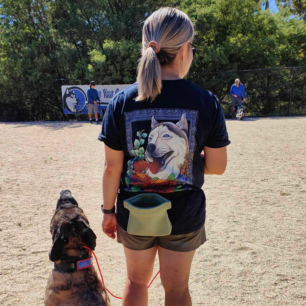 Woman with a beautiful tshirt design is standing with a dog in a dog training class.